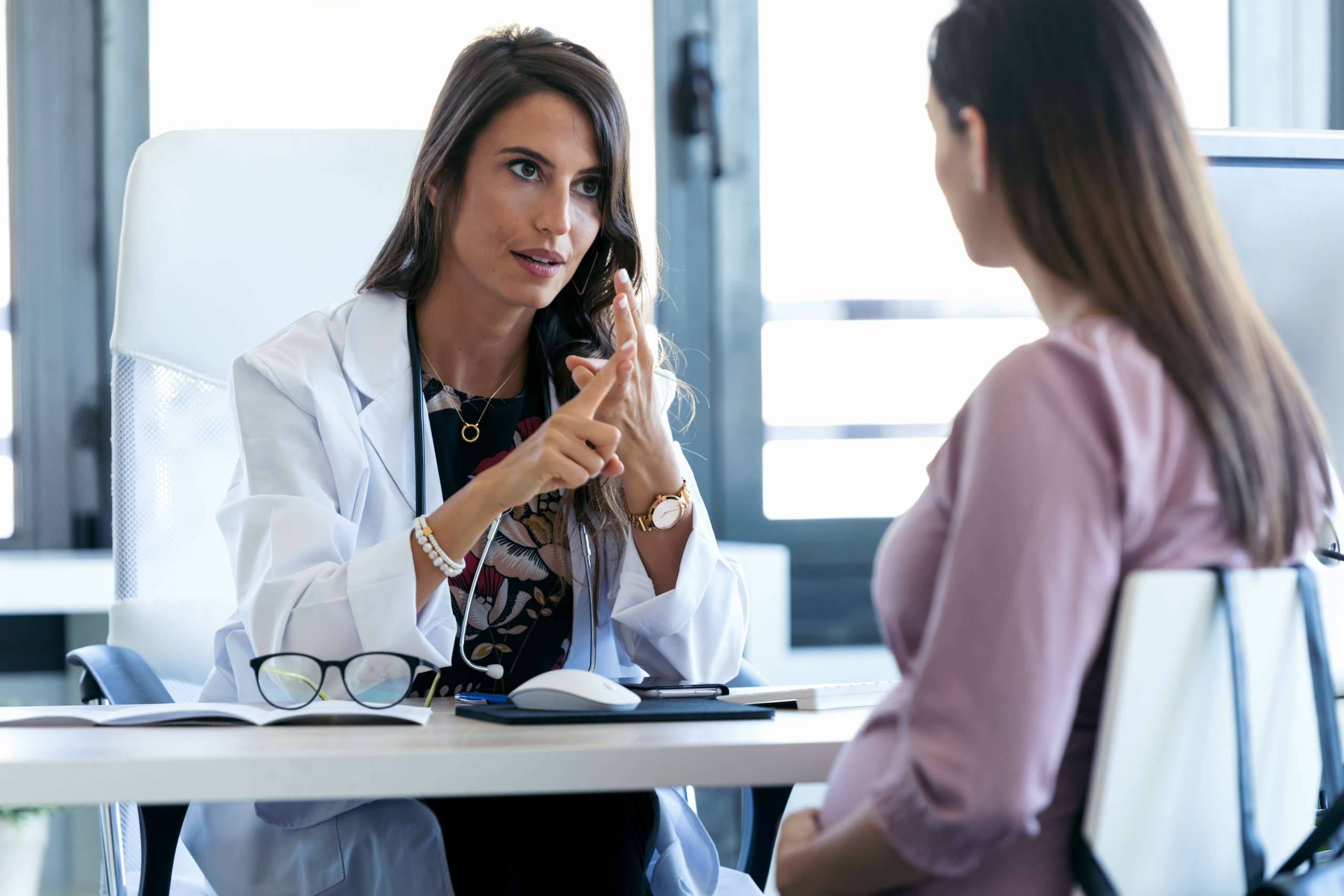 Shot of serious young gynecologist giving guidelines to his pregnant patient in the clinic.
