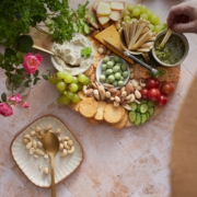 A platter of cheese, crackers, nuts, and vegetables