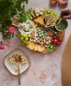 A platter of cheese, crackers, nuts, and vegetables