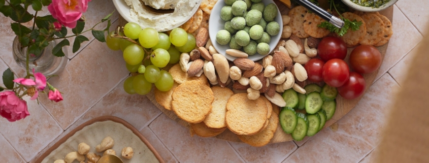 A platter of cheese, crackers, nuts, and vegetables