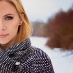 Beautiful blond woman in gray coat in winter nature